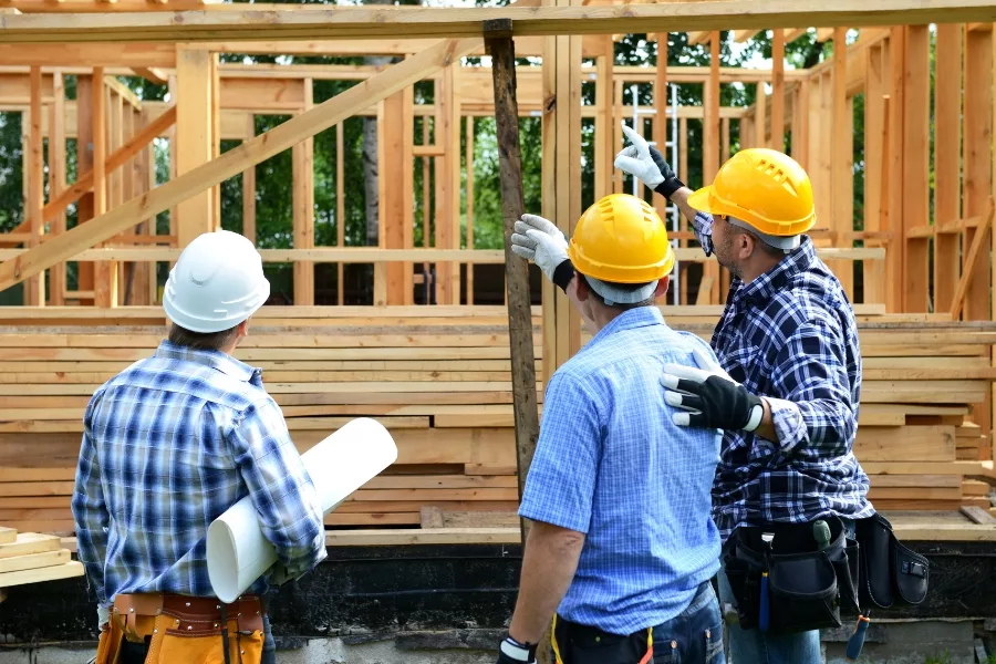 Construction crew reviewing plans at a wood-framed house