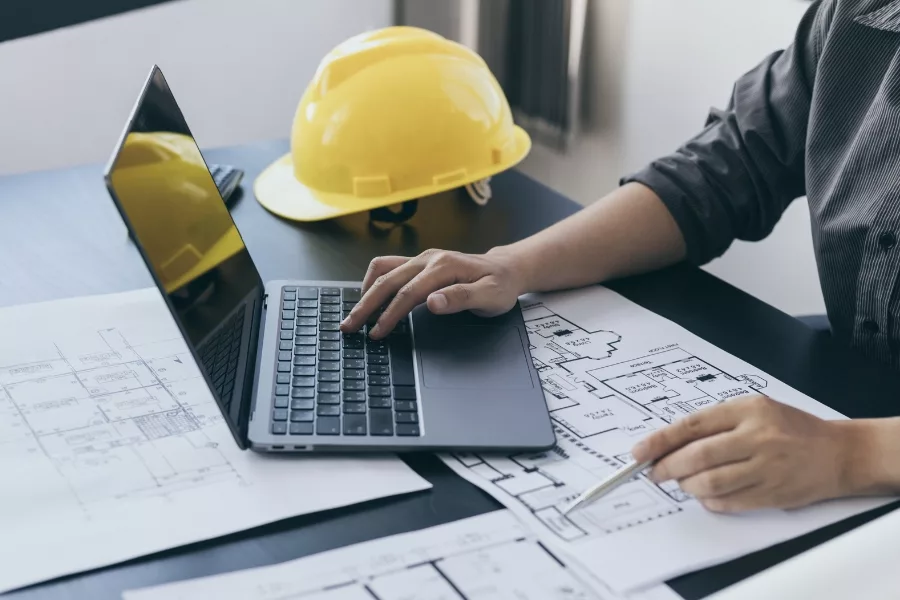 Drafting professional working with floor plans and a laptop